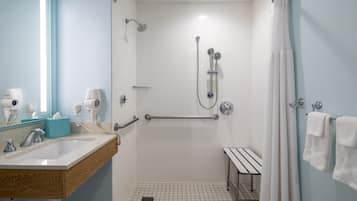 A modern bathroom with a shower, a sink, and a bench.