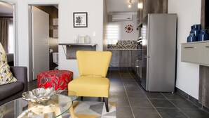 Une cuisine moderne avec une chaise jaune, une table en verre et un réfrigérateur.