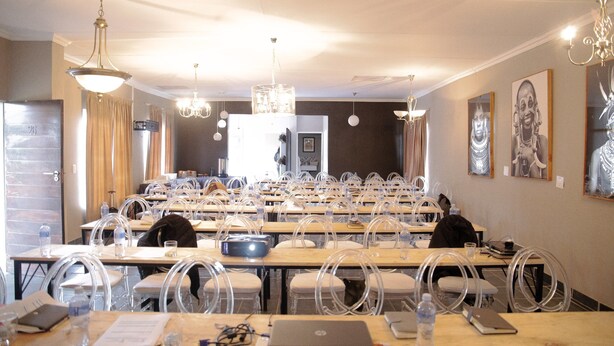 Une salle de conférence équipée de tables, de chaises et d’un lustre.