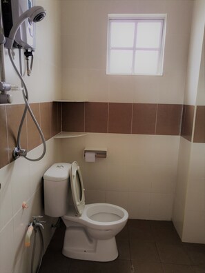 A bathroom with a toilet, a hand dryer, a paper towel dispenser, and a window.