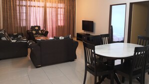 Un salon comprenant un ensemble de canapés, un téléviseur et une table à manger avec des chaises.