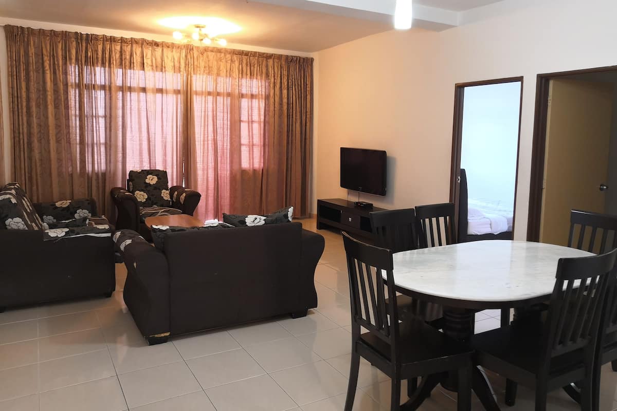 A living room with a sofa set, a TV, and a dining table with chairs.