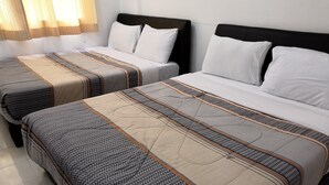 Deux lits jumeaux avec des couvre-lits à motifs, une tête de lit sobre et une fenêtre ornée de rideaux légers.