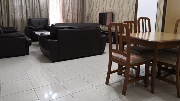 Un salon comprenant un ensemble de canapés, une table à manger avec des chaises, un ventilateur de plafond et un téléviseur.