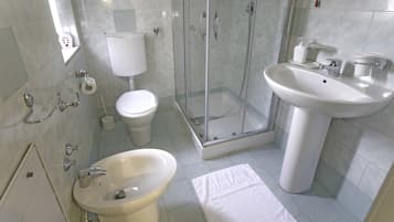 Une salle de bain comprenant des toilettes, un bidet, une douche et un lavabo.