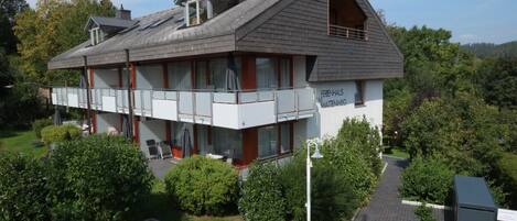 A two-story building with a sloped roof, a balcony on the upper floor, and a sign reading "Ferenhaus Mattingenweg".
