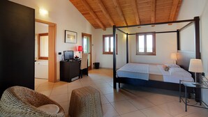 A spacious bedroom with a four-poster bed, a desk with a computer, and a wicker chair. - TENUTA AGANIS (Palazzolo dello Stella)