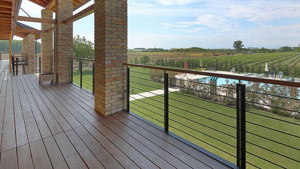 A wooden deck with a view of a vineyard and a swimming pool. - TENUTA AGANIS (Palazzolo dello Stella)