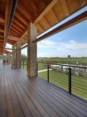 Um deck de madeira com vista para um vinhedo e uma piscina.