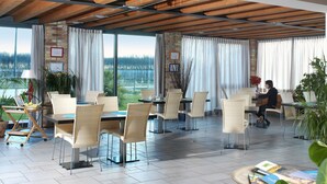 A spacious indoor dining area with natural light, wicker furniture, and a view of the outdoors. - TENUTA AGANIS (Palazzolo dello Stella)