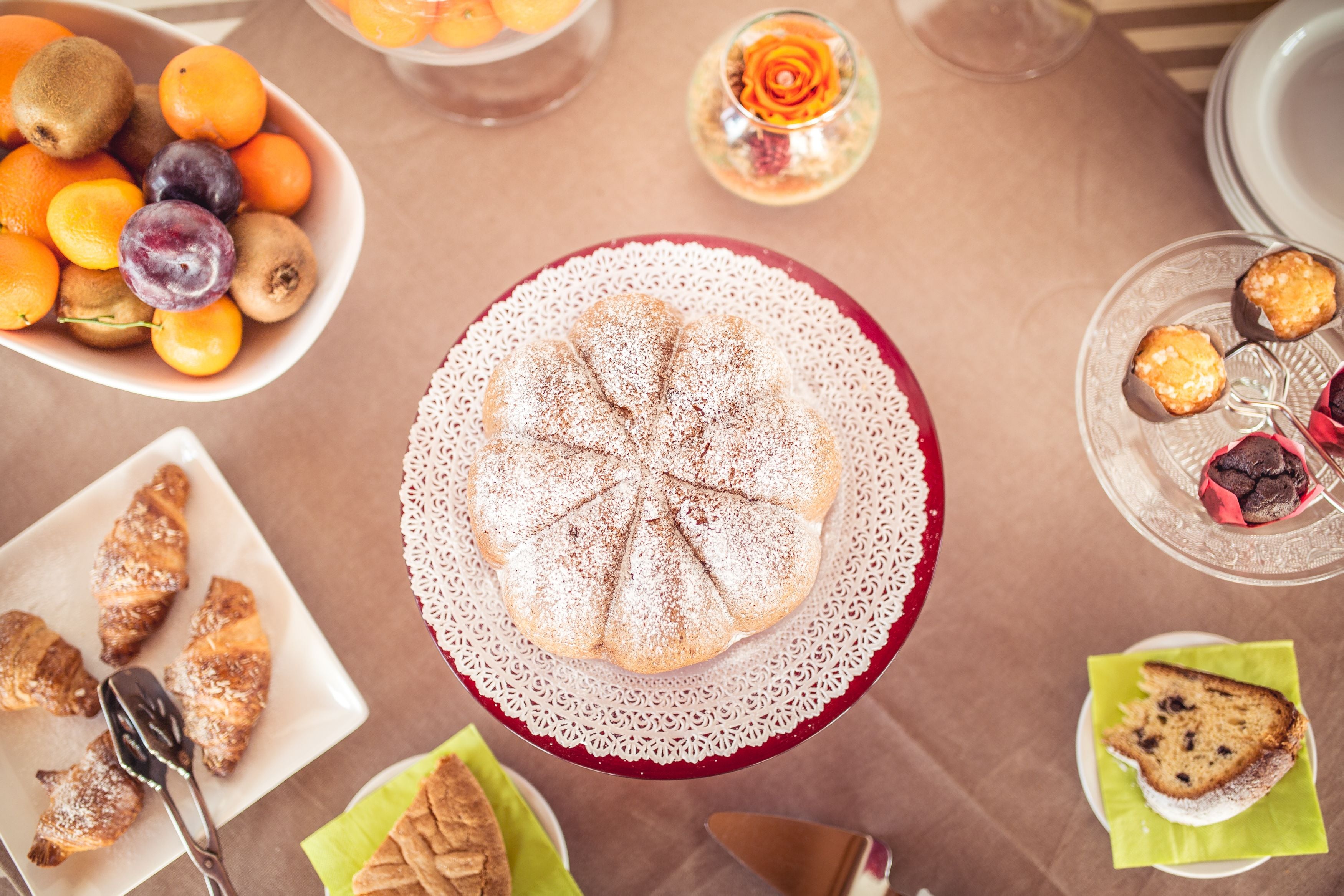 Ein Tisch mit verschiedenen Speisen, darunter eine große Torte, Gebäck und eine Schale Obst.