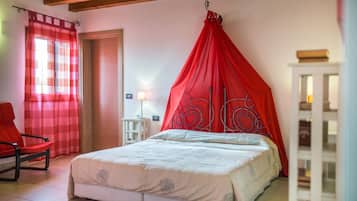 Un dormitorio con cama, una silla roja, una mesita de noche y una lámpara.