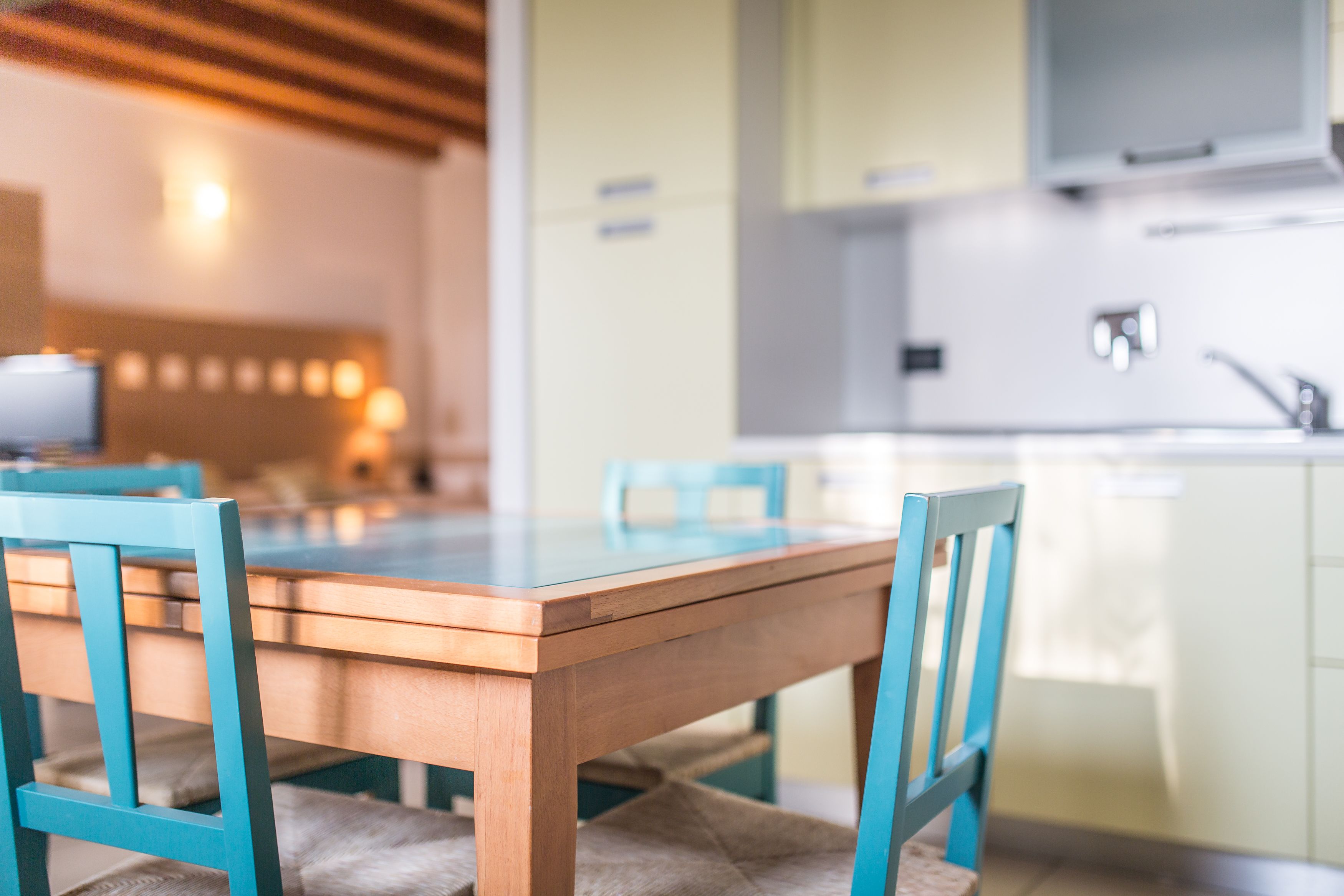 A modern kitchen with a wooden table and blue chairs, a white countertop, and a built-in oven.