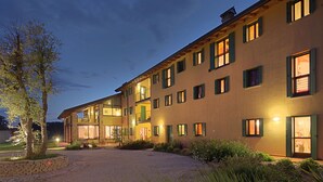A multi-story building with a courtyard, featuring a mix of balconies and windows, and a well-lit entrance. - TENUTA AGANIS (Palazzolo dello Stella)