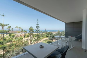 A balcony with a table and chairs, overlooking a beach and ocean. - Vichy Célestins Spa Hôtel Casablanca (Casablanca)