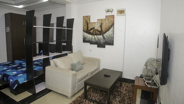 A modern living room with a sofa, coffee table, and artwork on the wall. - Capital & County Apartment Chevron (Lekki)