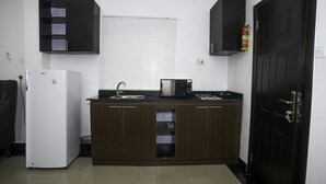 A compact kitchen with a refrigerator, sink, and cabinets. - Capital & County Apartment Chevron (Lekki)