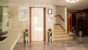 A hotel lobby with a marble floor, an elevator, a staircase, and recycling bins. - Hotel El Estadio (Mexico City)