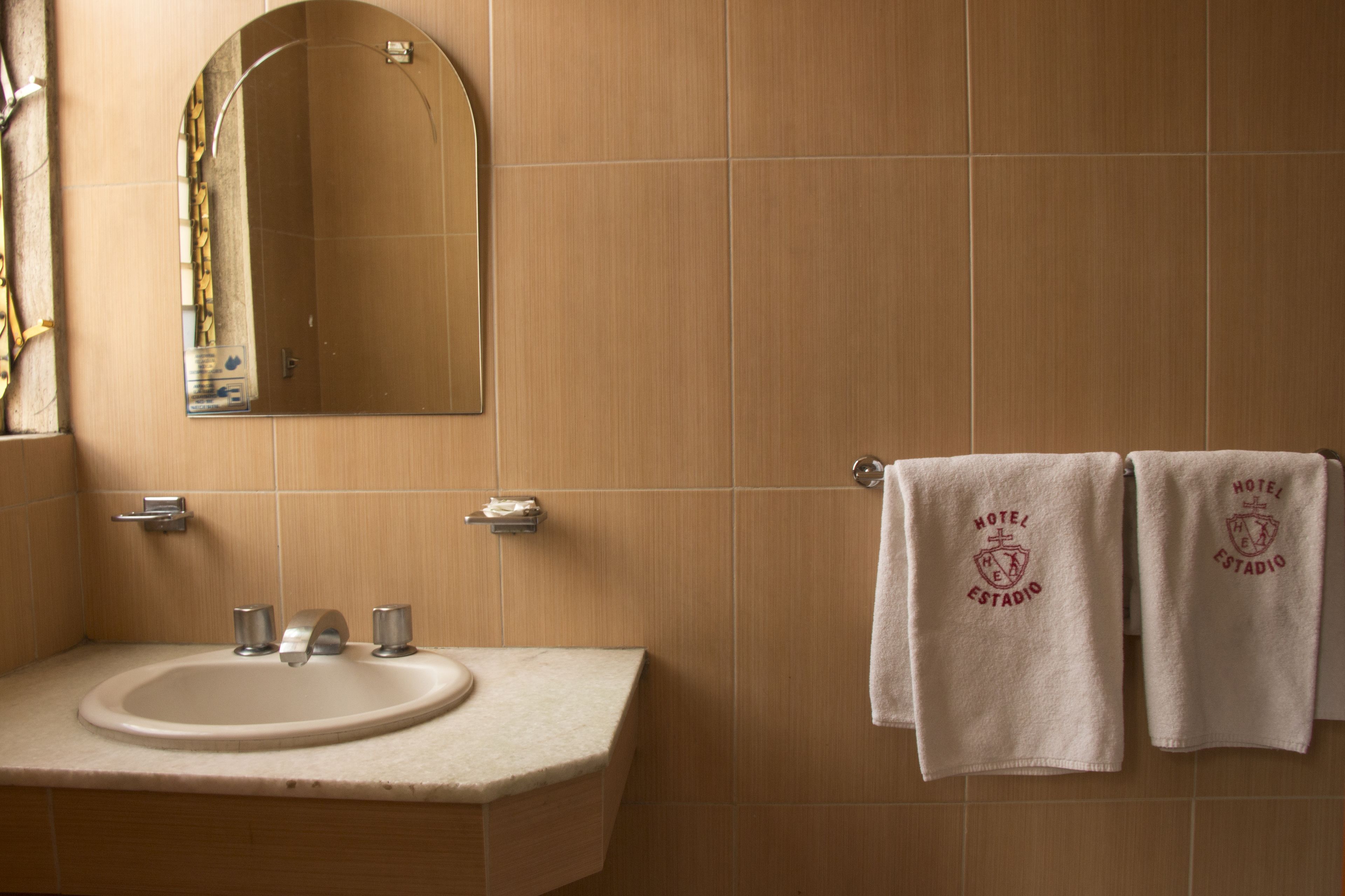 A bathroom with a sink, mirror, and two towels hanging on a towel rack.