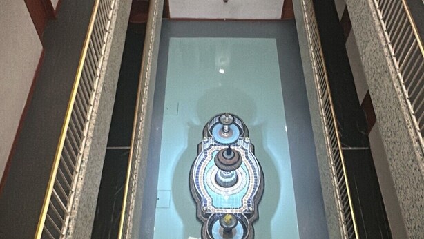 An indoor staircase with a central glass panel and a decorative metal railing. - Hotel El Estadio (Mexico City)