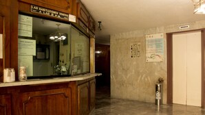 A hotel lobby with wooden cabinets, a marble floor, and a reception desk. - Hotel El Estadio (Mexico City)