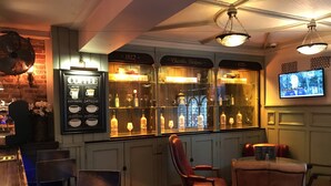 Zona de bar con tablero de menú, asientos y una pantalla de televisión.