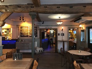 A cozy restaurant interior with wooden beams, a bar area, and a seating arrangement. - The Kings Head Hotel (Rochester)