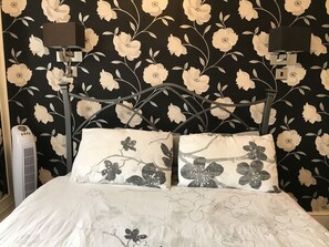 A bed with floral-patterned pillows and a black floral wallpaper background. - The Kings Head Hotel (Rochester)