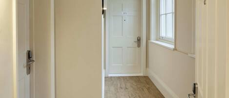 A hallway with a wooden floor, white walls, and a door marked with the number 203.