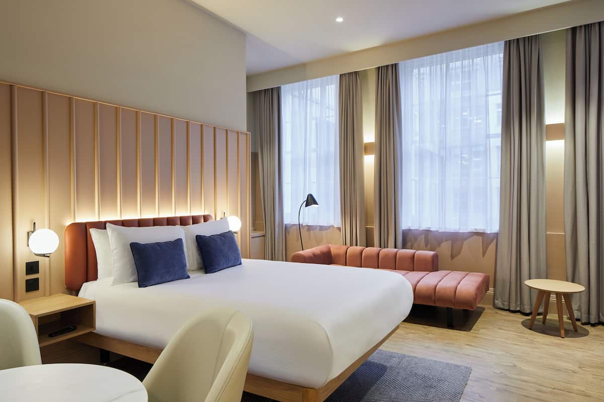 Une chambre d’hôtel moderne avec un grand lit, un canapé, une petite table et un bureau.