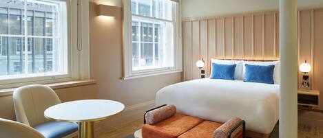 Una habitación de hotel con una cama grande, un sofá, una mesa redonda y dos ventanas.