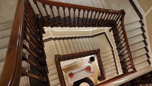 Un escalier en colimaçon avec des balustrades en bois et un revêtement de sol en moquette.