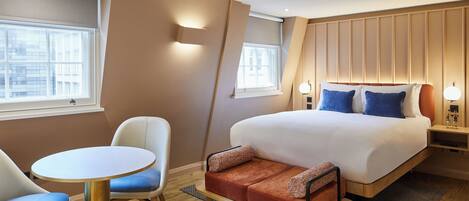 A hotel room with a bed, a sofa, a table, and chairs.