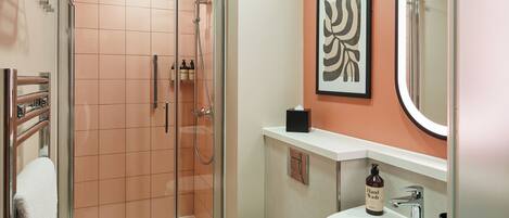 A modern bathroom with a glass-enclosed shower, a white sink, and a mirror.