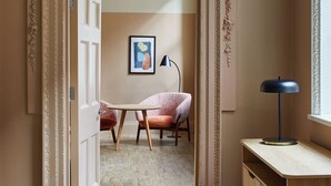 Une pièce comprenant un bureau en bois, une chaise, une lampe et un tableau encadré accroché au mur.