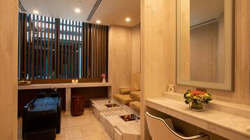 Bathroom features a large mirror, sink with marble countertop, and toilet, set against a wooden floor and walls.