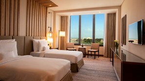 Een hotelkamer met twee bedden, een televisie, een bureau en uitzicht op de stad.