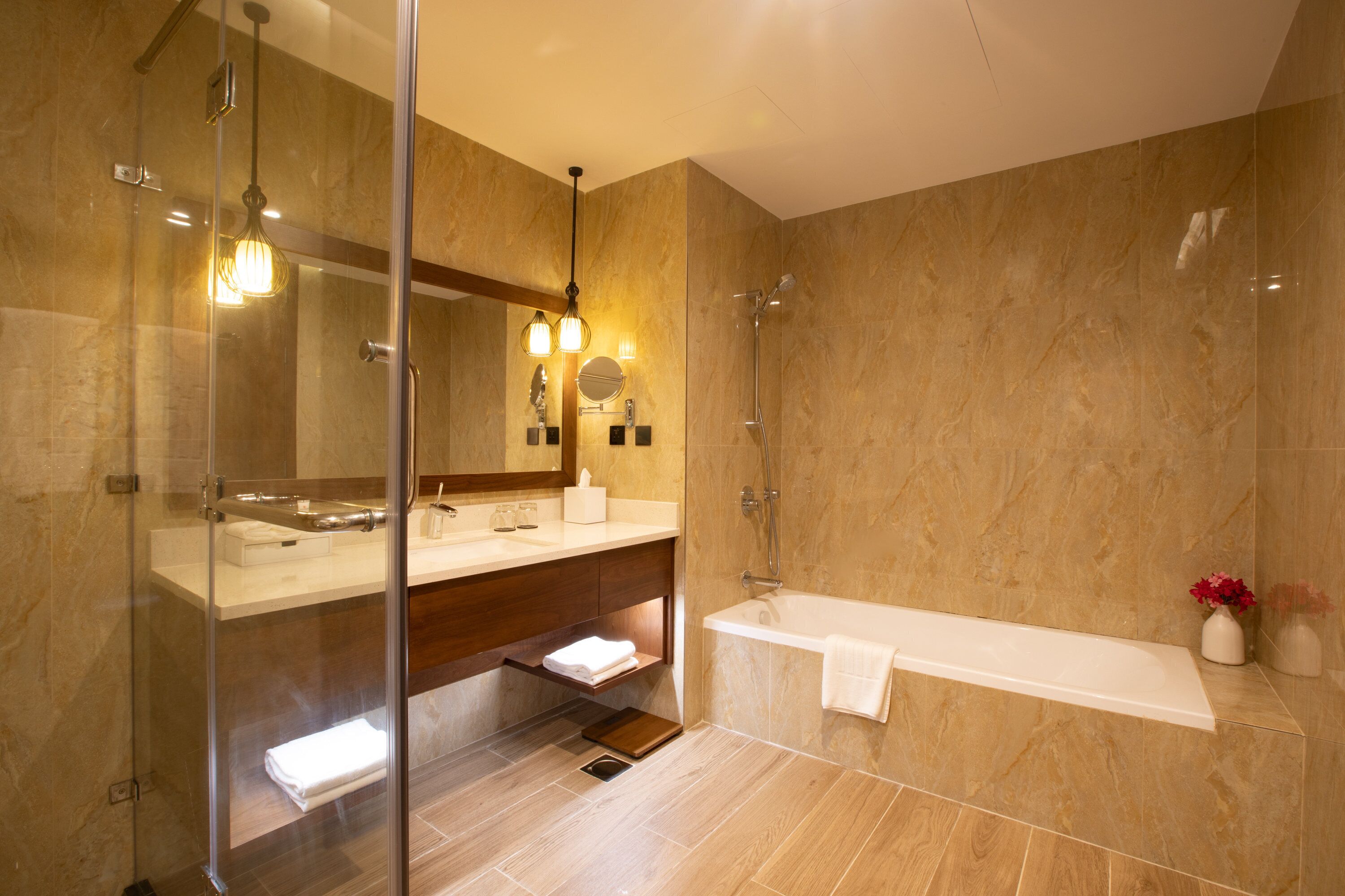 A modern bathroom with a glass shower enclosure, a bathtub, and a vanity with a mirror and towel rack.