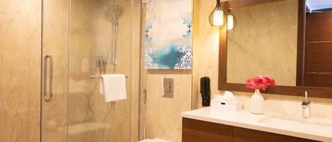 A modern bathroom with a glass shower enclosure, a white toilet, a sink with a mirror, and a vase with flowers.