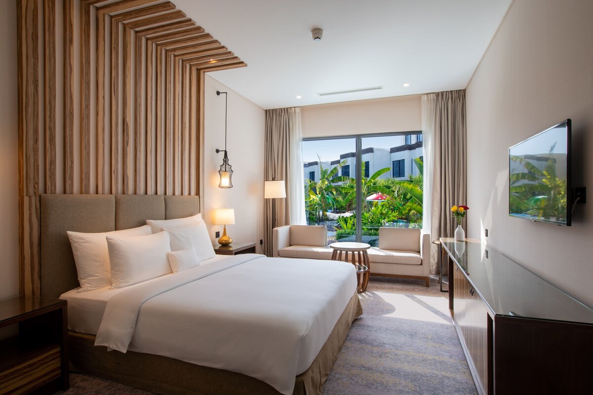 Een hotelkamer met een bed, een televisie, een bureau, een stoel en uitzicht op de omgeving.