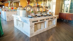 Enjoy a wide selection of dishes at our buffet, featuring multiple serving stations with plates, bowls, and utensils.