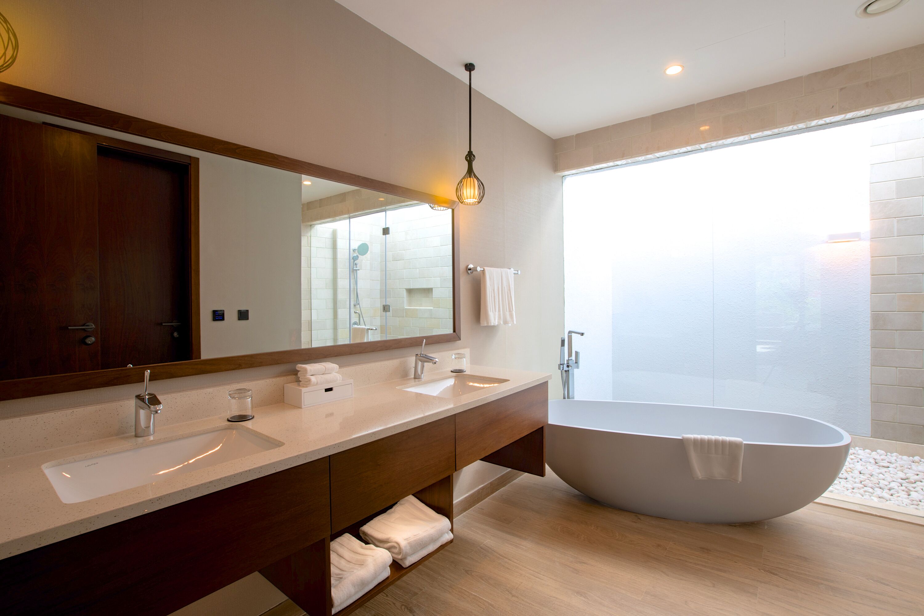 Un baño moderno con una bañera independiente, un espejo grande y un tocador con lavabo.