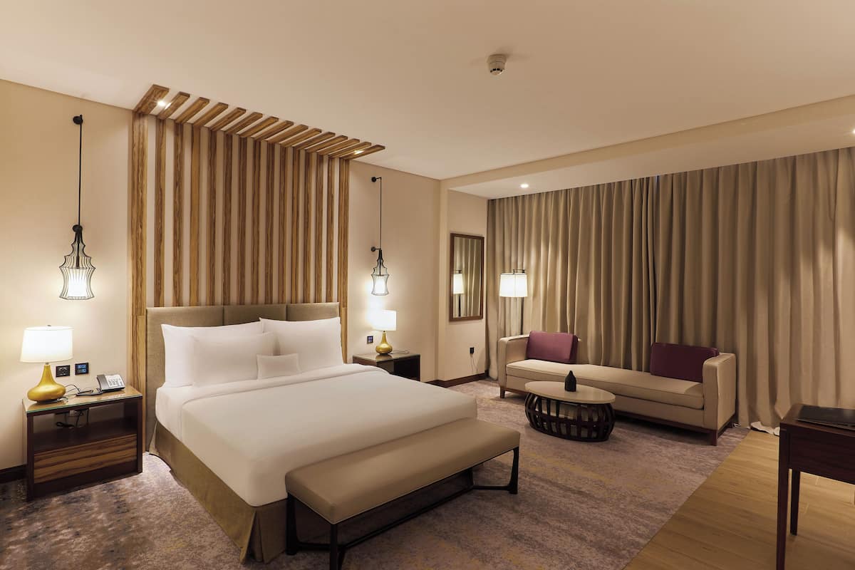 Una habitación de hotel con una cama grande, un sofá, una mesa de centro y un escritorio.