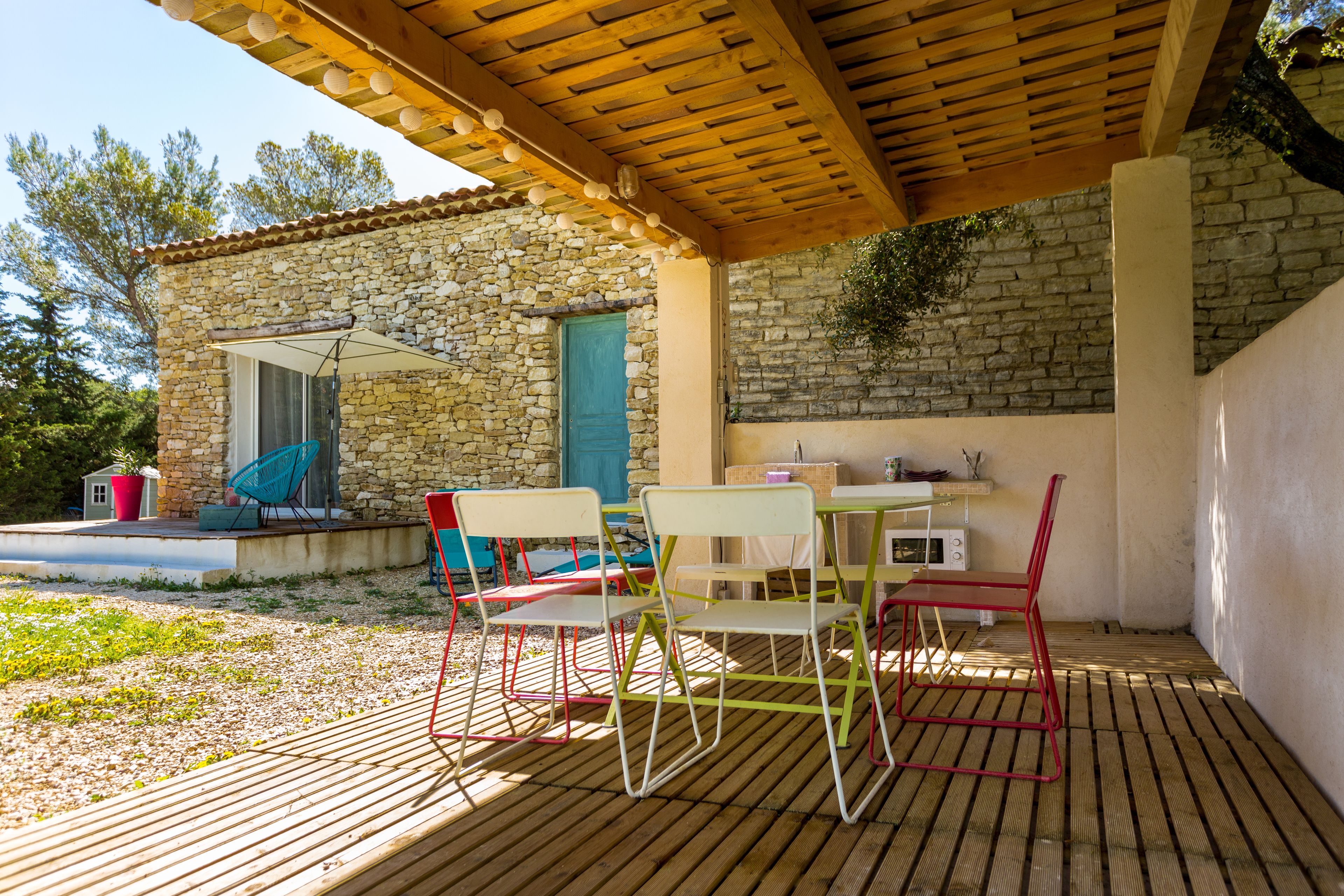 Une terrasse extérieure dotée d’une plateforme en bois, de murs en pierre et d’un espace abrité avec un plafond en bois.