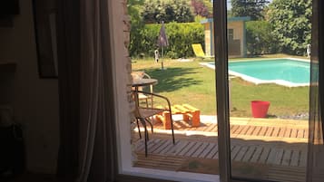 Een kamer met een schuifdeur naar een buitenruimte met een zwembad, een patio tafel en een stoel.