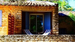 Un edificio de piedra con techo de tejas, una ventana con vistas y un muro de piedra al frente.