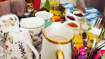 Ein Frühstücksbrett mit verschiedenen Gegenständen, darunter ein Teekessel, Tassen, eine Karaffe und Besteck.