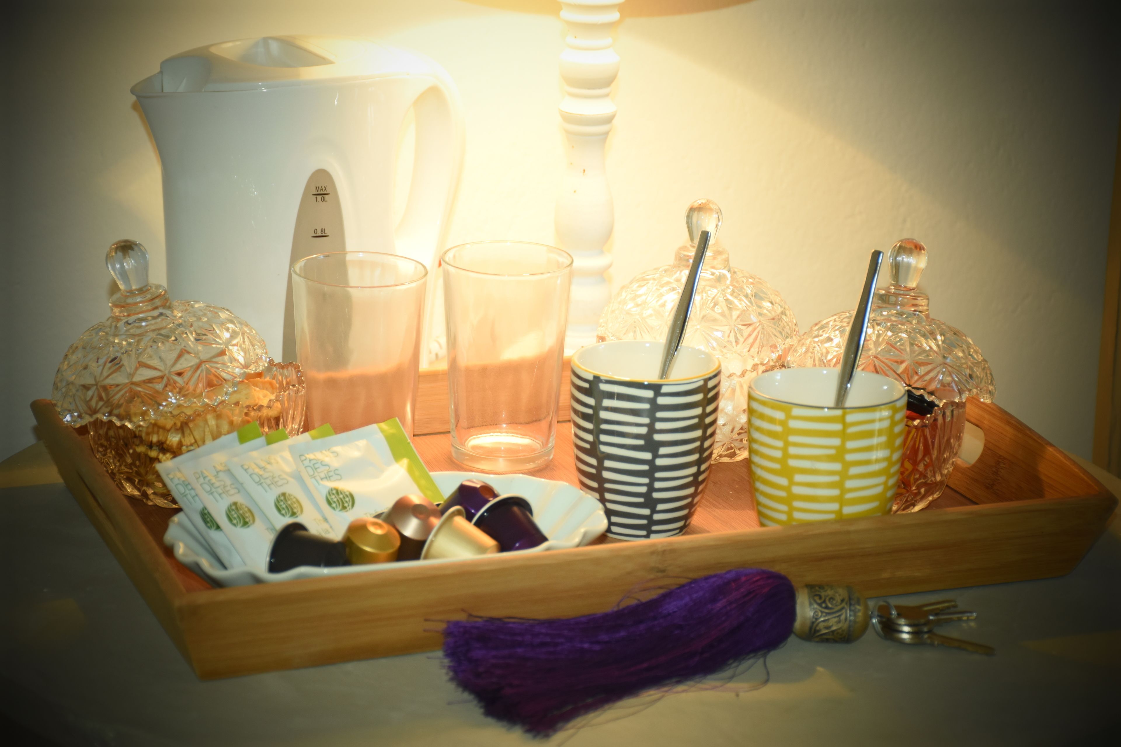 A tray with a white pitcher, two glasses, a patterned mug, and a decorative item.