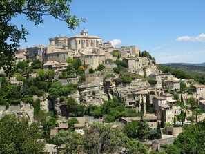 Pueblo histórico construido sobre una ladera rocosa, con edificios de piedra tradicionales y una iglesia destacada.
