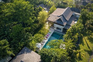 An aerial view of a house with a swimming pool surrounded by lush greenery. - Casa ola Villa (Canggu)